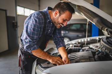 Car mechanic work under car hood in garage, maintaining vehicle engine