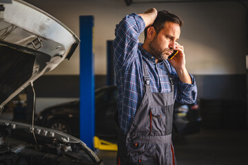 Car mechanic speak on mobile phone with concerned expression at work