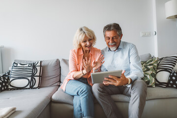 Happy senior couple talking to family over a video call on digital tablet