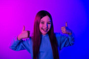 Canvas Print - Photo of cheerful pretty little lady dressed hoodie showing two thumbs up empty space isolated neon purple color background