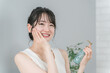 © buritora - スキンケア・紫外線対策・美白・保湿をする椅子に座った笑顔のアジア人女性