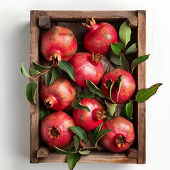 Pomegranates with leaves in wooden box on white background.