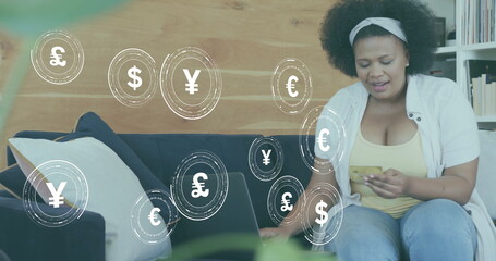 Wall Mural - Image of currency icons and data over african american woman paying online with card