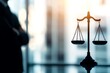 © Gunn - Silhouette of a legal balance scale with a blurred professional in the background, symbolizing justice, equality, and legal profession.