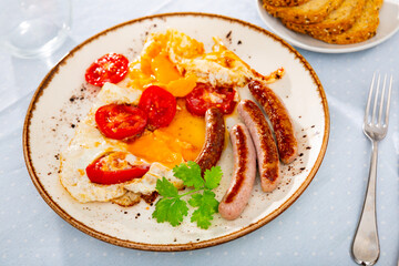 Appetizing breakfast with scrambled eggs, sausage and tomatoes