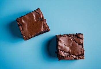 Close-up of two brownie pieces on a blue background, top view. Dessert photography, chocolate treat, baked goods, sweet indulgence, delicious brownies. Ai generated image