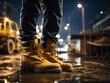 © shrinay - Construction worker's boots on a wet ground with construction site  at night