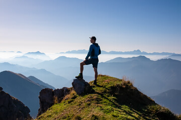 Silhouette of hiker man in alpine landscape of Gailtal Alps, Carinthia, Austria. Panoramic view of majestic hazy mountain ridges of Julian Alps, Karawanks, Carnic Alps. Peaceful tranquil atmosphere