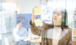 © dodotone - Business asian woman using glass board note ideas paper at indoors office