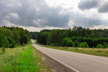 A road with trees in the background and a cloudy sky