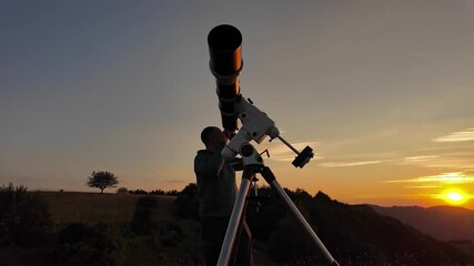 Wall Mural - Amateur astronomer looking at the evening skies, observing planets, stars, Moon and other celestial objects with a telescope just before sun down.	
