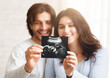 © Prostock-studio - Happy young couple looking at sonography picture of their baby, selective focus on ultrasound scan in their hands