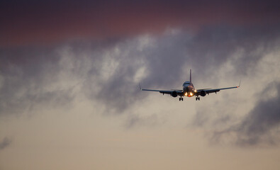 Wall Mural - Passengers commercial airplane flying above clouds in sunset light. Concept of fast travel, holidays and business.