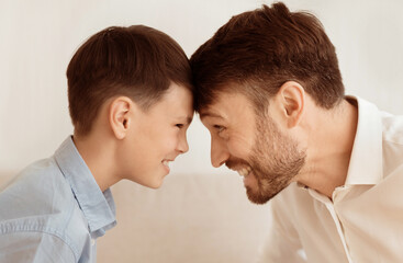 Wall Mural - Weekend With Dad. Happy Father And Son Bowing Heads Touching Foreheads Playing Over White Background.