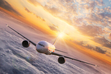 Wall Mural - Passengers commercial airplane flying above clouds in sunset light. Concept of fast travel, holidays and business.