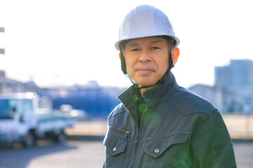 Supervisor of a manufacturing site wearing a white helmet with a machine tool in the background.