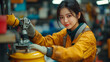 © feeling lucky - A focused female technician in a workshop wearing an orange uniform, showcasing her skills and dedication in a mechanical environment.