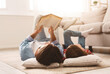 © Prostock-studio - Little daughter and daddy enjoying time together, laying on floor at home, man reading book to his cute daughter, empty space