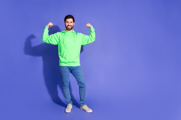 Full body photo of attractive young man show muscles flexing dressed stylish green clothes isolated on violet color background