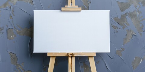 A wooden easel holding a blank canvas against a grey wall, offering space for artistic expression and text.