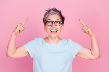 Canvas Print - Photo of pretty aged woman indicate fingers up empty space blue t-shirt isolated on pink color background