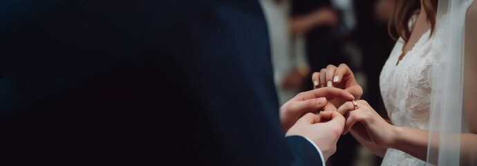 Wedding hands of the bride and groom ceremonially put wedding rings on their fingers. AI generated.