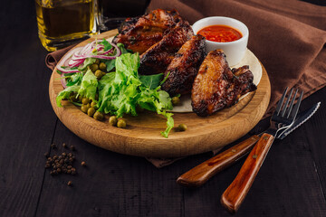 Grilled chicken wings served with salad on wooden board