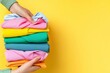 © auc - A vibrant collection of neatly folded clothes in various colors against a cheerful yellow background.