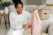 © Maria Vitkovska - Happy customer unpacking fashionable clothes from cardboard box at home