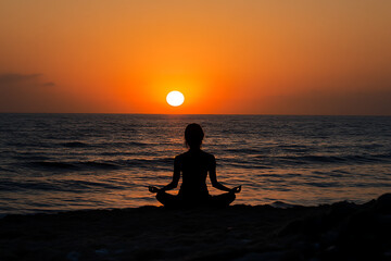 Wall Mural - A person meditating on a beach at sunset, promoting peace and mindfulness.