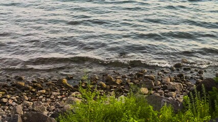 Poster - Gentle waves lapping against the rocky shore of Bracciano Lake, Italy. The calm water ripples over the stones, creating a serene lakeside atmosphere.