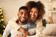 © Prostock-studio - Christmas eve. Loving couple embracing and smiling to camera in front of Christmas tree
