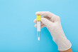 © fotoduets - Doctor hand in white rubber protective glove holding empty transparent plastic tube for urine or other analysis test on light blue background. Pastel color. Healthcare concept. Closeup. Front view.