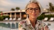 © iuricazac - Middle-aged woman with a content smile, relaxing in a resort environment, wearing a stylish shirt and eyeglasses.