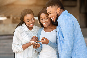 Poster - Funny content. Cheerful african american friends watching videos on smartphone, spending time together outdoors