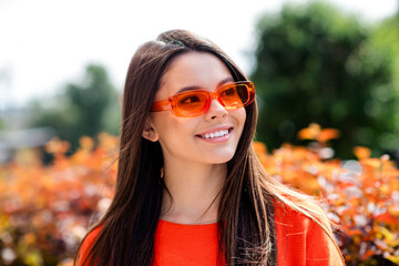 Wall Mural - Photo of pretty teen good mood girl sunglass summer vacation look empty space wear red clothes walk outside urban city park