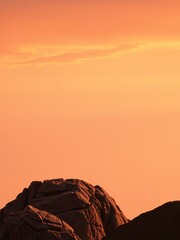 Wall Mural - Silhouettes of rocks against a fiery sunset.