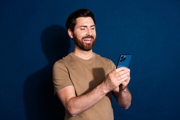 Aufkleber - Photo of young handsome guy brunet hair model in beige t shirt using smartphone communicating isolated on dark blue color background