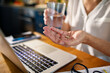 © Marko Geber - Close up senior woman taking supplements or vitamins while working on laptop at home