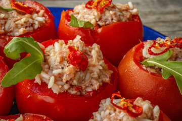 Close-up of stuffed tomatoes filled with a spicy rice mixture and topped with sun-dried tomatoes and fresh arugula. Bright red tomatoes make for a tasty and appetizing presentation.