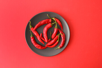 Plate with hot pepper on red background.