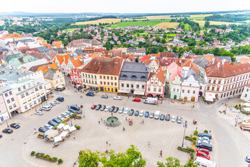 An overhead perspective showcasing Zizka Square with its historic buildings, parked cars, and lush surroundings on a cloudy day. Tabor, Czechia