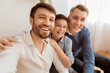 © Prostock-studio - Male generations. Happy adult man with son and elderly father making selfie smiling sitting on sofa at home.