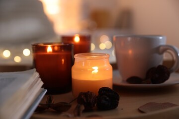 Wall Mural - Burning candles, cup of drink and decor on tray indoors, closeup. Autumn atmosphere