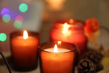 Wall Mural - Burning candles and cone on table, closeup. Autumn atmosphere