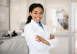 © Prostock-studio - Portrait Of Beautiful Professional Black Female Stomatologist Posing In Clinic Interior, Happy African American Dentist Lady Standing With Folded Arms And Smiling At Camera, Ready For Check Up