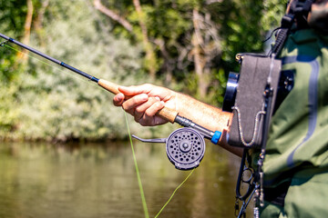 Close-up of man holding fly fishing rod by river