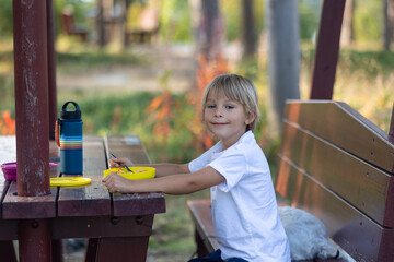 Cute blond child, eating lunch in a campside along the road in Norway