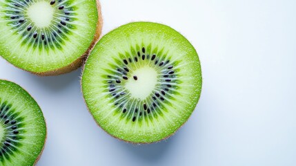 A fresh kiwi sliced in half, showing the bright green flesh and black seeds, placed on a white background.