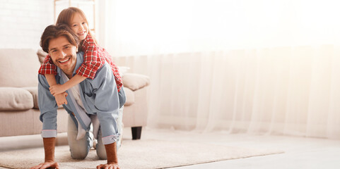 Wall Mural - Father and daughter spending weekend together at home. Little girl riding fathers back in kid bedroom, copy space